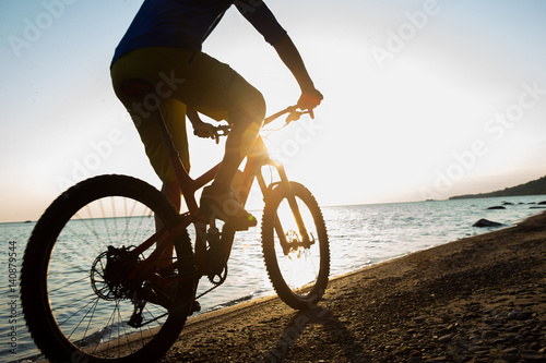 Obraz na płótnie Man riding a mountain bike on the beach w salonie