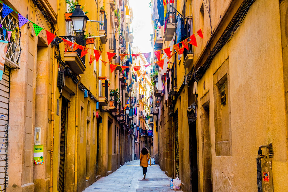 Naklejka premium kobieta spaceruje po starej ulicy w starym centrum barcelony w wiosenny dzień