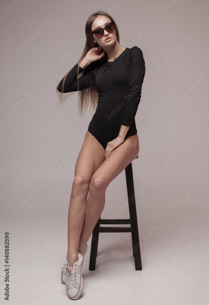 Naklejka premium Sexy brunette woman posing in erotic lingerie, looking at camera. Perfect slim body