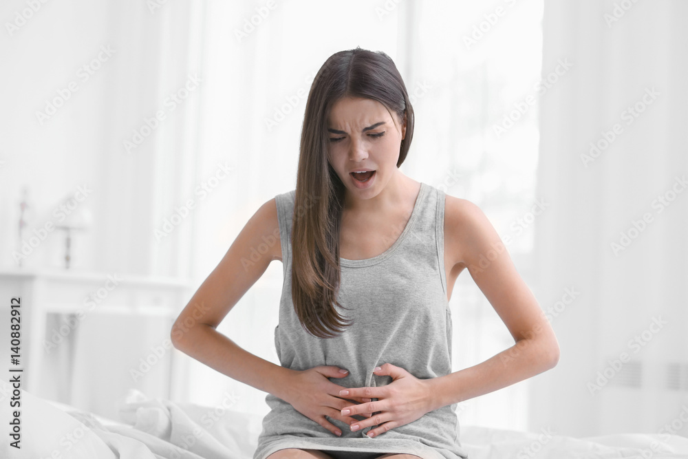 Young woman suffering from abdominal pain at home. Gynecology concept Young woman suffering from abdominal pain at home. Gynecology concept