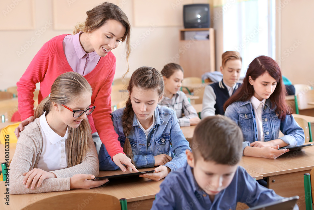 Pupils and teacher in classroom working with tablet computer Pupils and teacher in classroom working with tablet computer