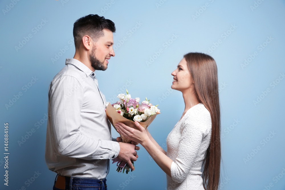 Happy young couple with bouquet of flowers on light background Happy young couple with bouquet of flowers on light background