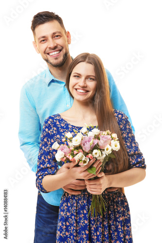 Happy young couple with bouquet of flowers on white background