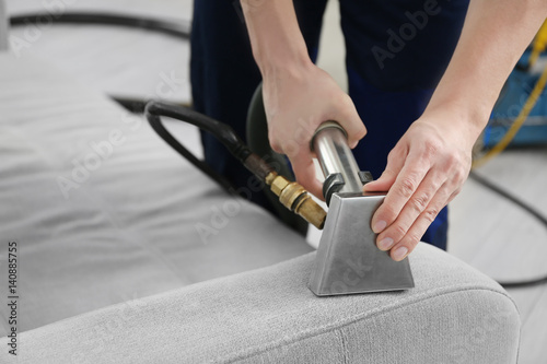 Dry cleaner's employee removing dirt from furniture in flat, closeup