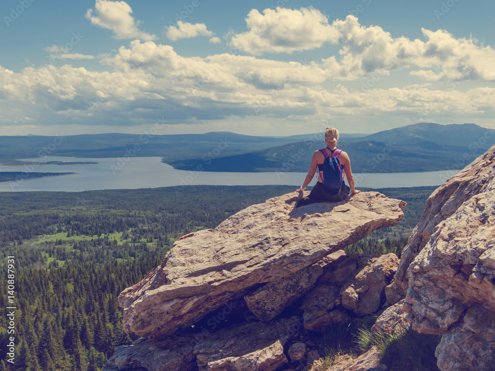 Fototapeta premium The girl sits back on top of the mountain