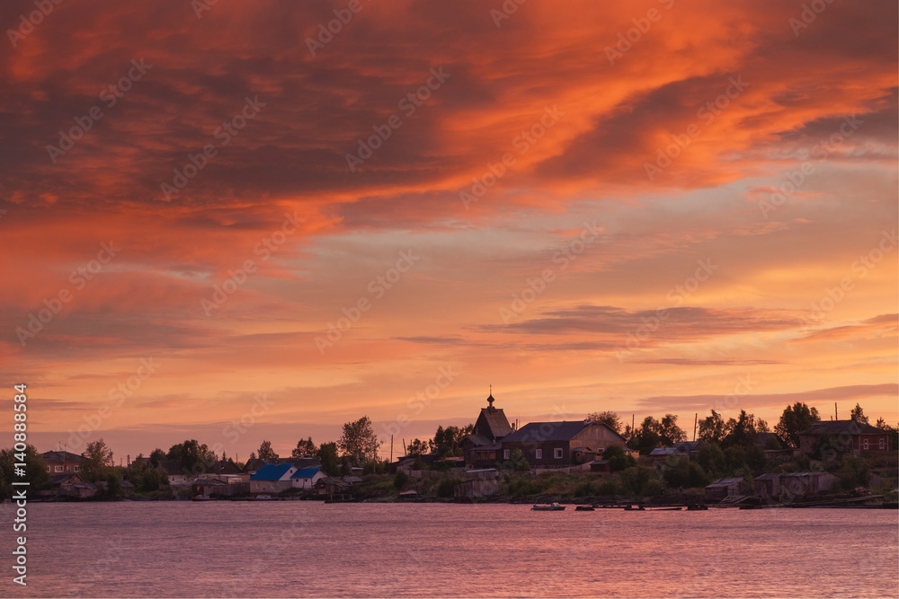 Beautiful sunset sky and clouds after a thunderstorm. Village Rabocheostrovsk, Republic of Karelia, Russia, the coast of the White Sea. A beautiful sunset in red tones over the village