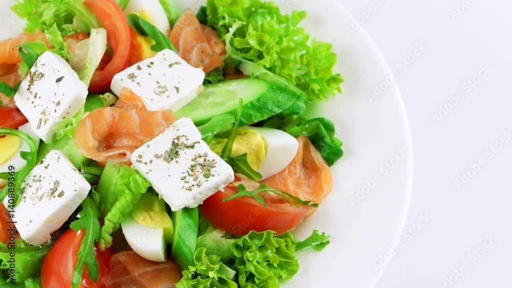 Edge of plate with Salmon salad with feta cheese, boiled eggs, lettuce leaf, arugula and tomatoes, copy space in right side, loop
Edge of plate with Salmon salad with feta cheese, boiled eggs, lettuce leaf, arugula and tomatoes, copy space in right side, loop