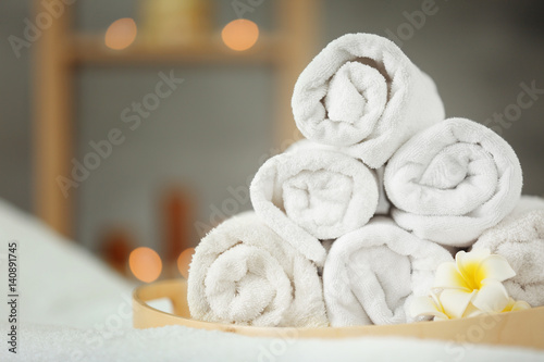 Wooden tray with pile of towels in spa salon