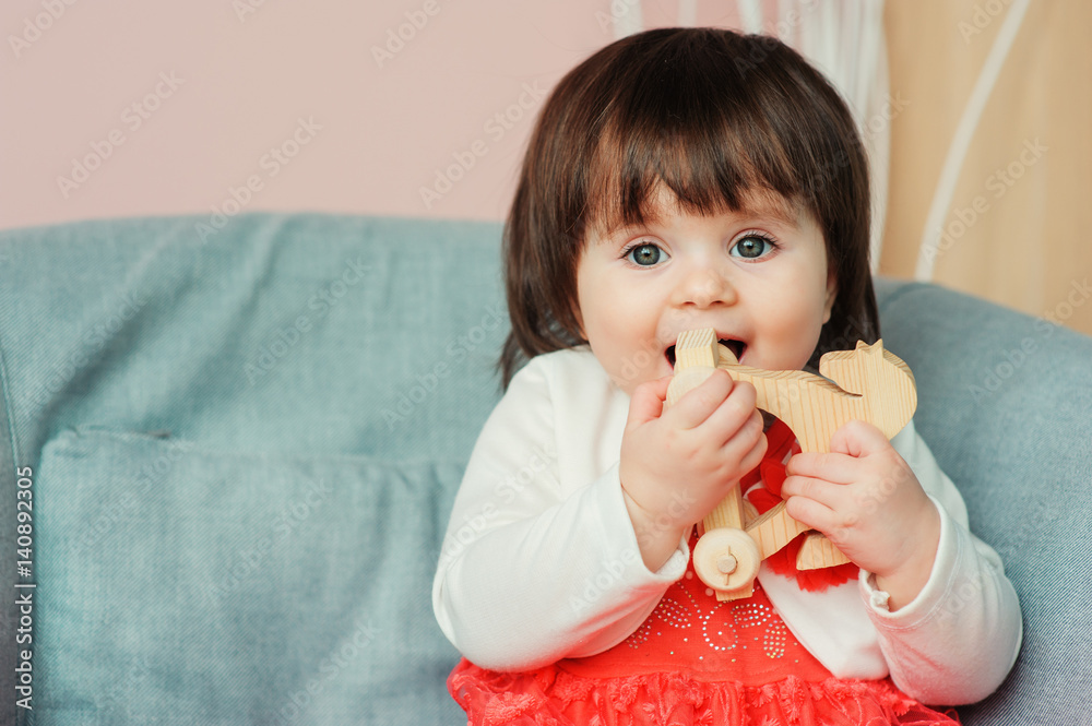 cute happy 1 year old baby girl playing with wooden toys at home. Modern nursery interior, early learning concept cute happy 1 year old baby girl playing with wooden toys at home. Modern nursery interior, early learning concept