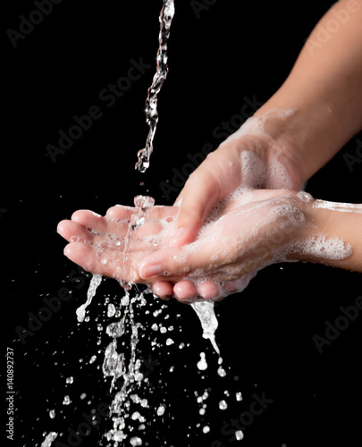 Washing of hands with splashing water on black background