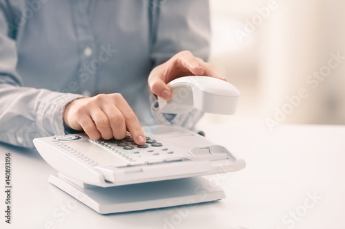 Woman dialing telephone number in office