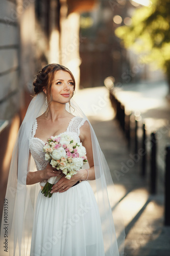 Gorgeous bride looks up in the sky standing on summer street