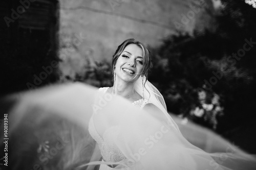 Look at laughing bride over her veil blown by wind