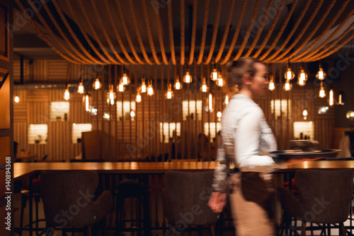 A slow exposure of a waitress serving drinks against light lamp decor glowing