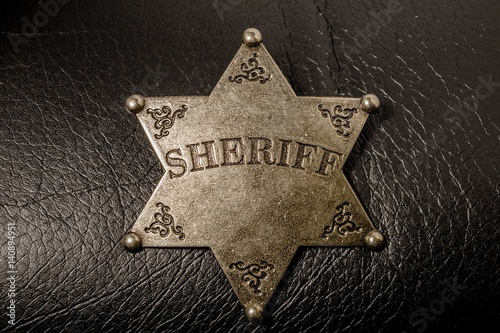 Sheriff badge on black leather texture background. Macro shot.