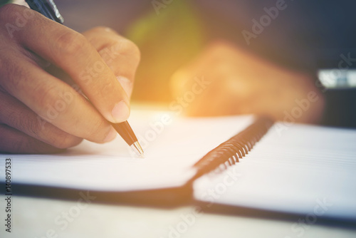 Young man hands writing on book in office.Businessman working on desk of wood.Business.