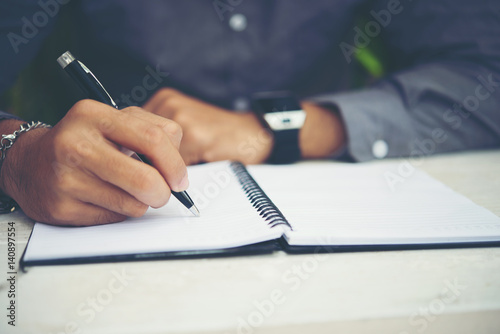 Young man hands writing on book in office.Businessman working on desk of wood.Business.