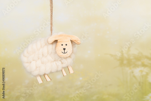 Wooden and woll decoration sheep on a green spring background
