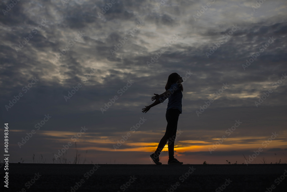 Silhouette of woman praying over beautiful sky background