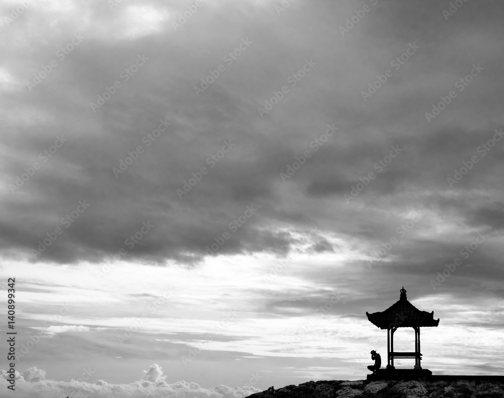 Fototapeta Silhouette of lonely sad man sitting under the cloudy sky
