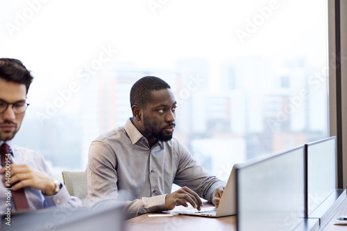Black business executive sitting at a desk using laptop