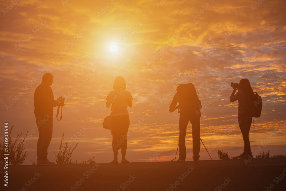 Group of people standing in an open field watching the sunse