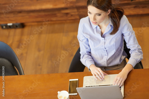 High angle view of an young brunette working at her office desk with laptop.