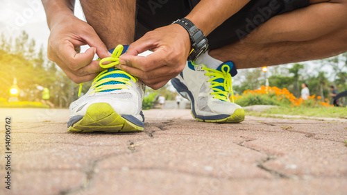 Bilde på lerret Runner man tying running shoes laces getting ready for race on road
