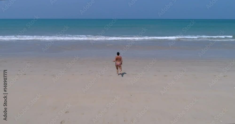 Attractive woman running to swim in the sea. View from above. Aerial. Attractive woman running to swim in the sea. View from above. Aerial.