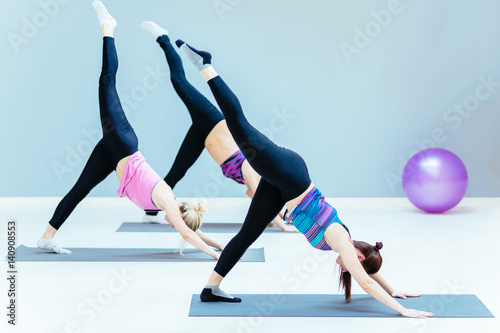 Group of young people doing stretching exercises in the fitness studio