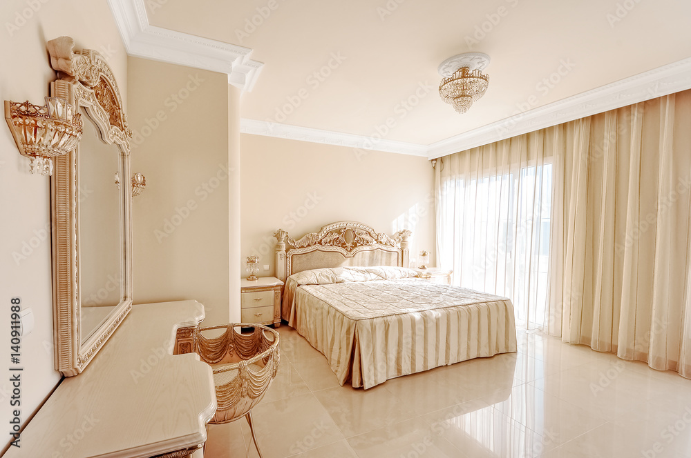 Luxurious bedroom in pastel colours in a neoclassical style, with a large bed and a dressing table, with marble floors.
