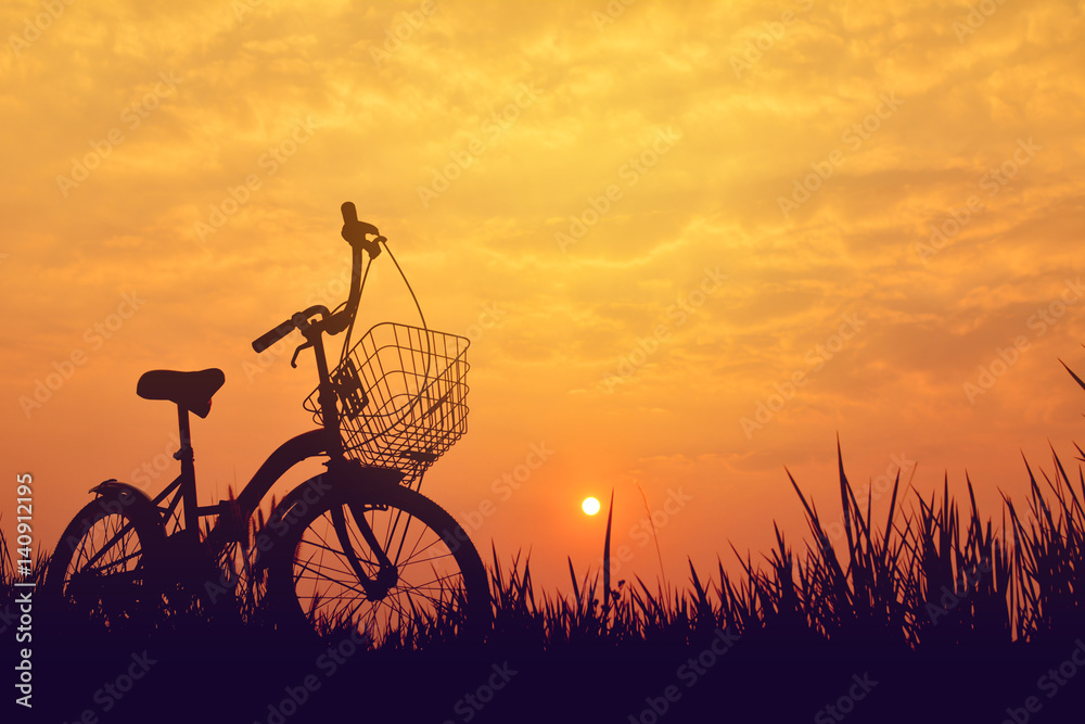 Silhouette of bicycle on grass with the sky sunset Silhouette of bicycle on grass with the sky sunset