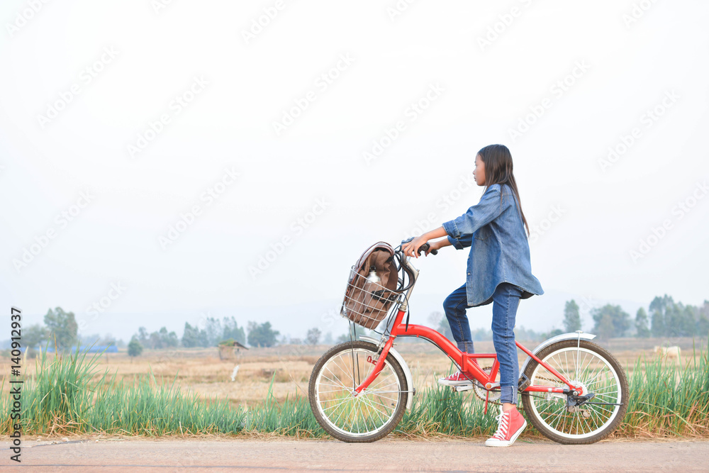 Happy girl with bicycle on grass field, selective and soft focus, concept travel in holiday