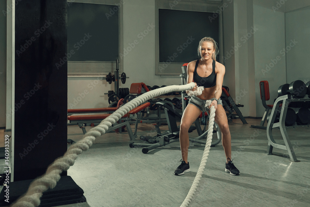 Beautiful girl in the gym doing an exercise with a rope