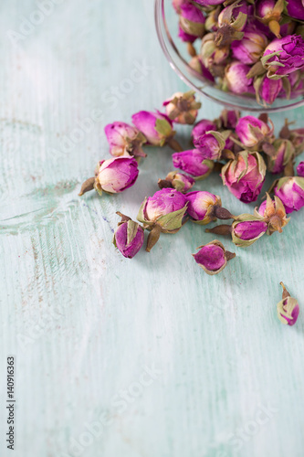 dried rose buds on turquoise wooden surface