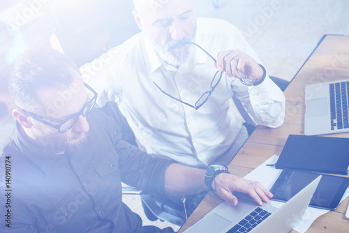 Group of two partners making research for new business direction in modern office.Young bearded businessman working on modern laptop.Business people meeting concept.Visual effects.