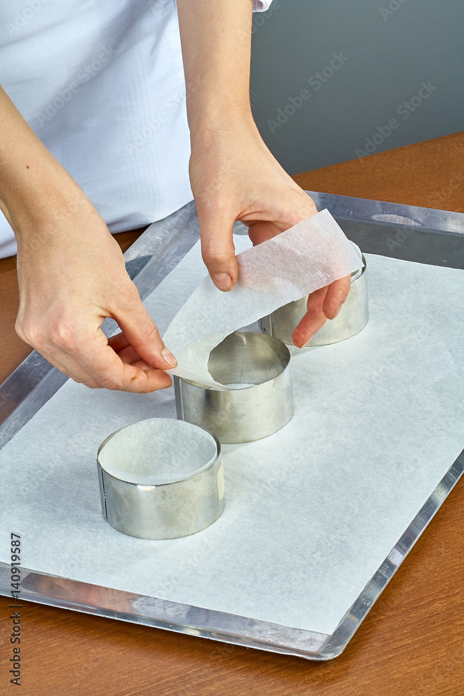 The cook pours the dough into forms for making cupcakes The cook pours the dough into forms for making cupcakes