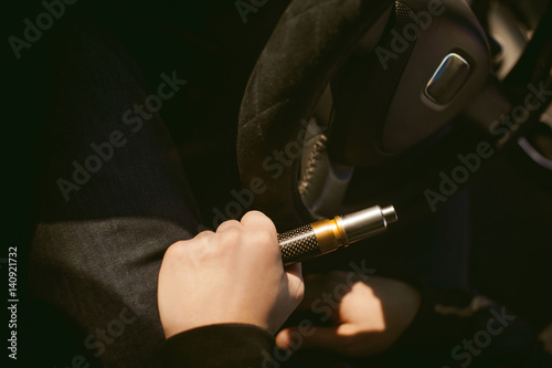 young vaper man with beard vaping mechanical mod. Guy smokes an electronic cigarette by blowing a smoke vapor. Holds in hand Sitting at the wheel of a car background
