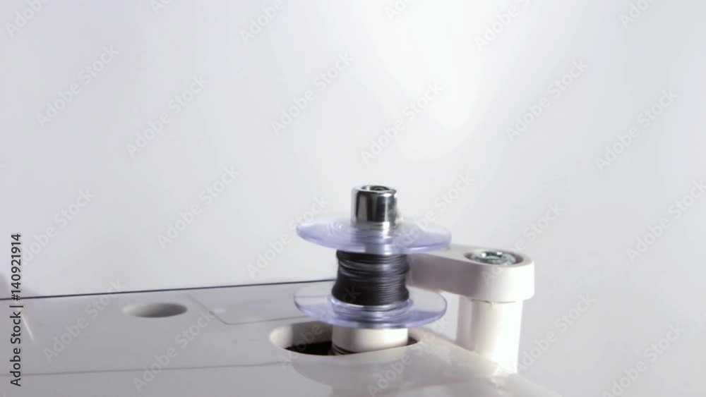Shot of a sewing bobbin being wound up on a sewing machine with black thread. Shot of a sewing bobbin being wound up on a sewing machine with black thread.