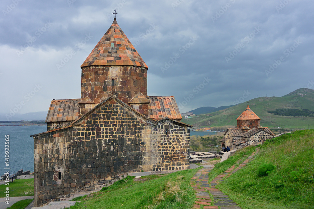 The tourists visit Sevanavank Monastery, located on Sevan Peninsula, among the bright green hills