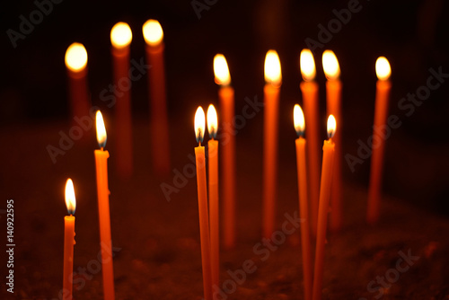 long lighted candles group on dark background.