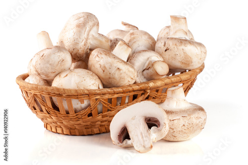 Champignon mushrooms in a wicker basket isolated on white background