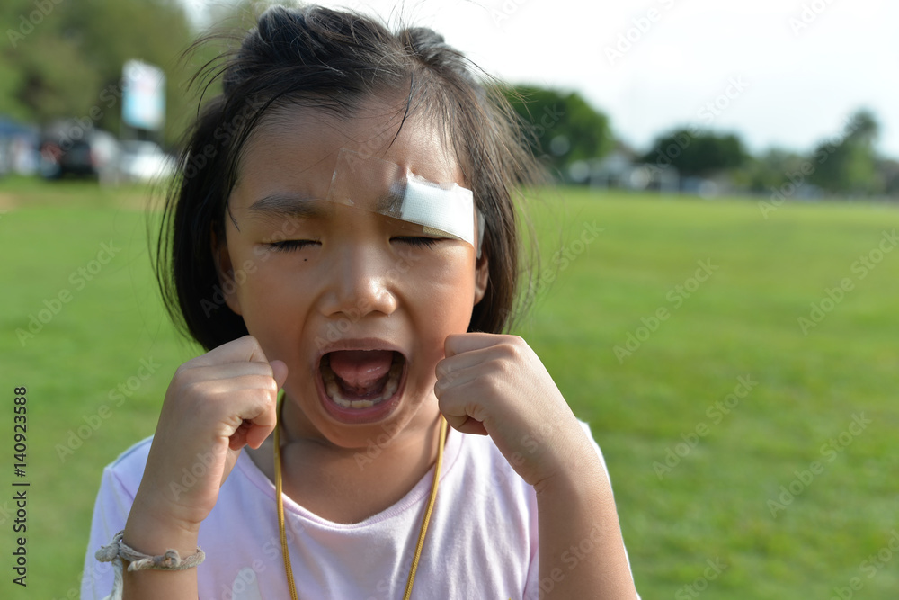 Little cute girl with plaster on eyebrows,girl hurt and cry at green