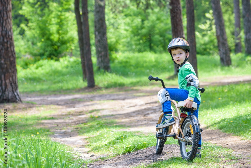 Happy cute blond kid boy having fun his first bike on sunny summer day, outdoors. child making sports. Active leisure for children Happy cute blond kid boy having fun his first bike on sunny summer day, outdoors. child making sports. Active leisure for children