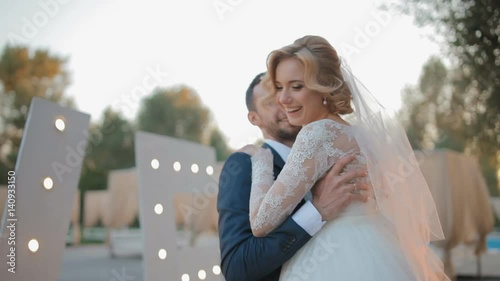 Bride and groom spinning around in front of the decoration with bulbs