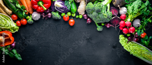 Fresh vegetables, chili, onion, garlic, herbs and spices.On a black wooden background. Free space for text . Top view