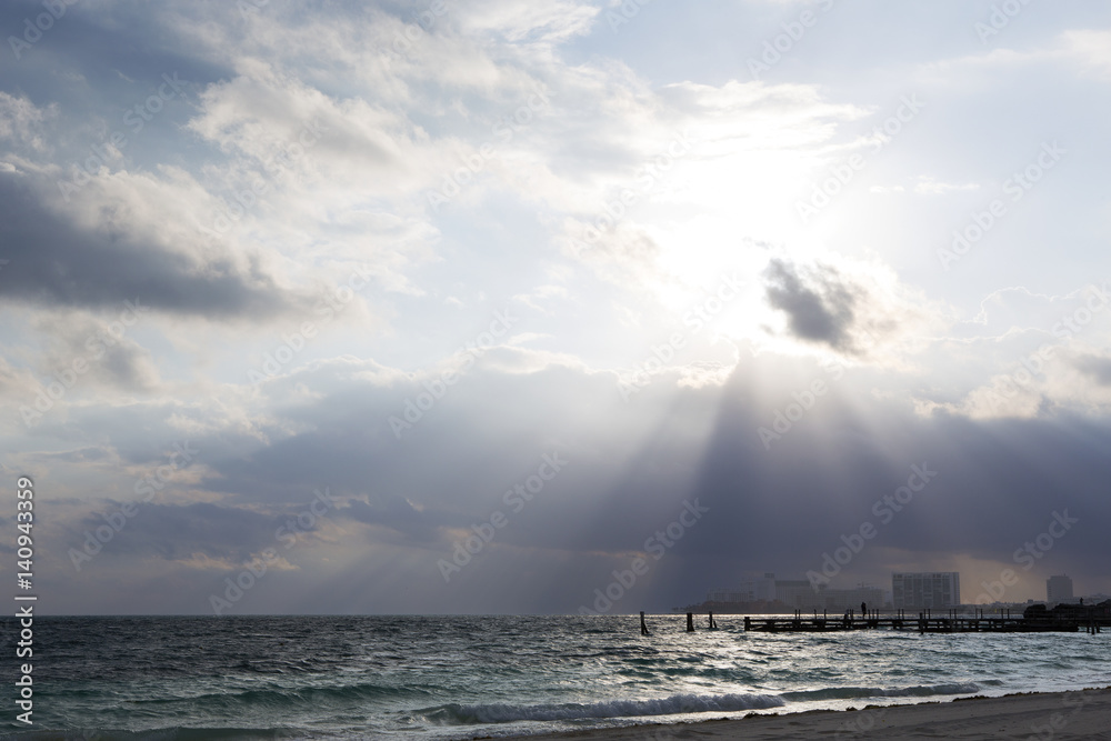 Dramatic light rays coming from the clouds on a beach. Light illuminates the city.
