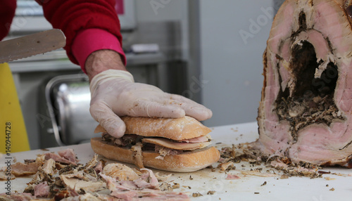 hand of chef slicing the meat of pork to prepare a sandwich