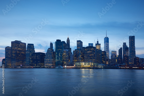 New York city skyline with illuminated buildings in the blue evening hour