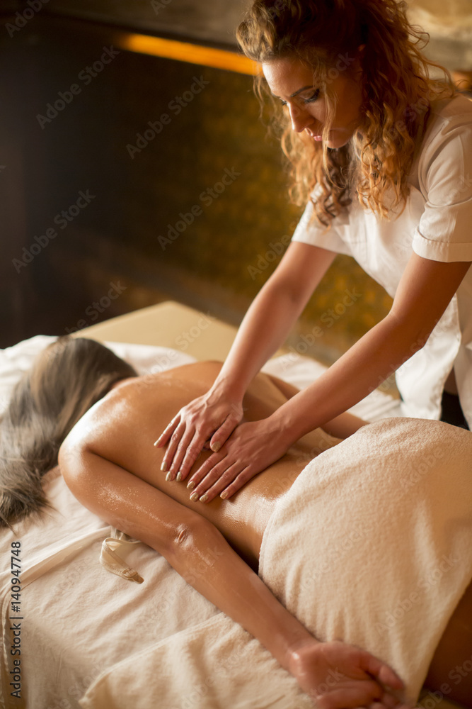 Obraz premium Beautiful brunette spa woman getting massage on towel in spa salon